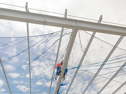 A worker is installing net on the roof